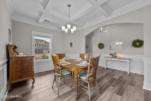 dining room featuring beamed ceiling, arched walkways, a notable chandelier, and wood finished floors