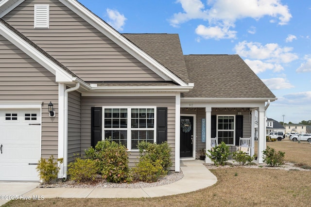 view of front of property with an attached garage, covered porch, and roof with shingles