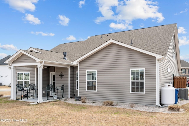 back of house featuring a yard, central AC, a patio, and a shingled roof