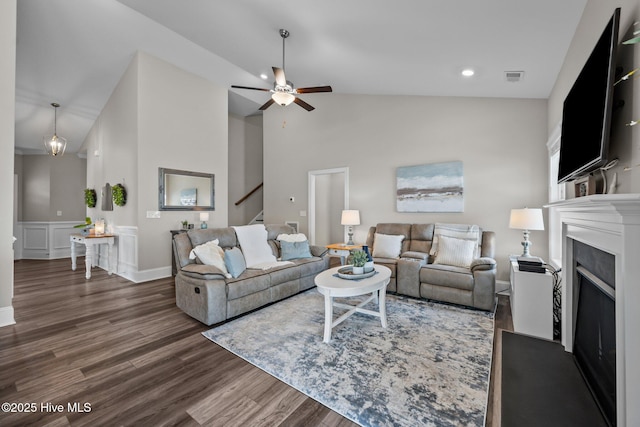 living room featuring visible vents, ceiling fan, stairway, a fireplace, and wood finished floors