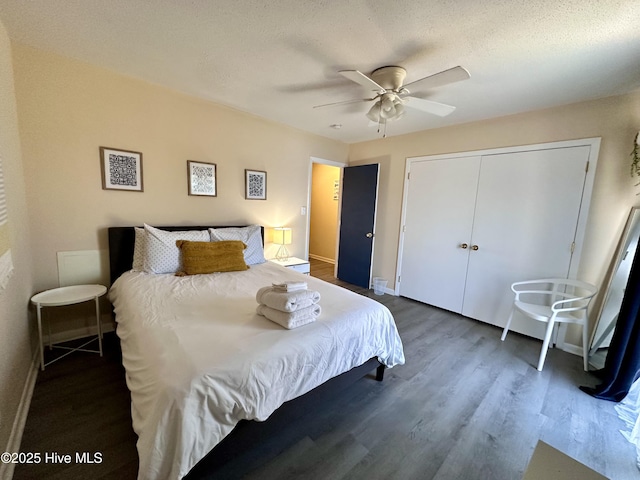 bedroom featuring baseboards, dark wood finished floors, a closet, a textured ceiling, and a ceiling fan