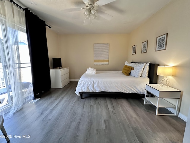 bedroom featuring ceiling fan, baseboards, and wood finished floors