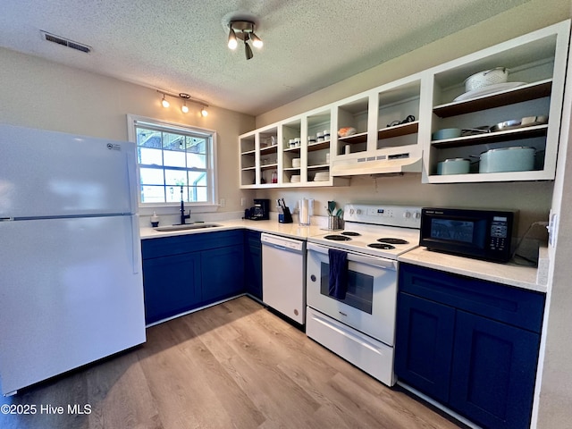 kitchen featuring visible vents, blue cabinetry, under cabinet range hood, white appliances, and a sink