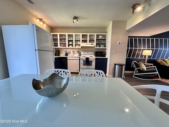 kitchen with under cabinet range hood, wood finished floors, white appliances, a textured ceiling, and open shelves