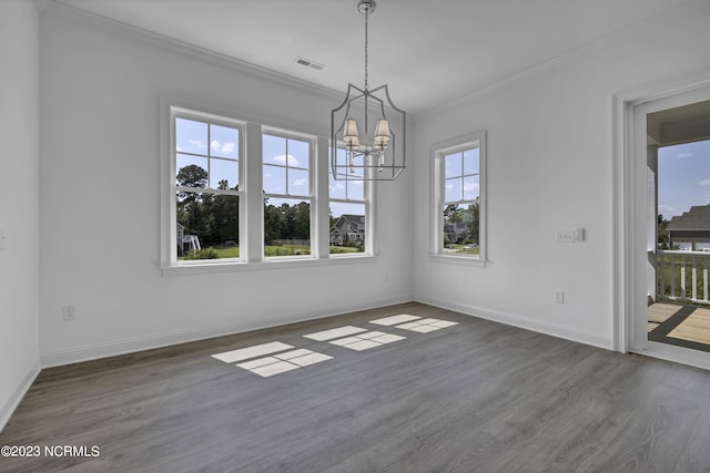 unfurnished dining area featuring visible vents, baseboards, ornamental molding, an inviting chandelier, and wood finished floors