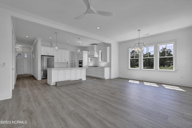 unfurnished living room with wood finished floors, baseboards, recessed lighting, ornamental molding, and ceiling fan with notable chandelier