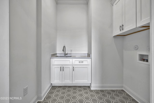 laundry room featuring a sink, baseboards, hookup for a washing machine, and cabinet space