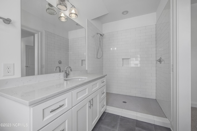 bathroom with a tile shower, tile patterned flooring, and vanity