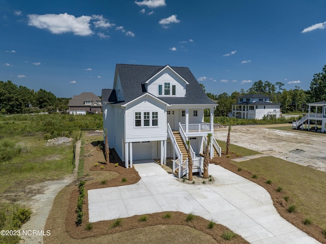 beach home featuring a shingled roof, stairway, a porch, a garage, and driveway