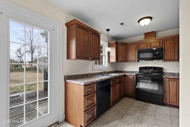 kitchen featuring visible vents, a sink, hanging light fixtures, black appliances, and dark countertops