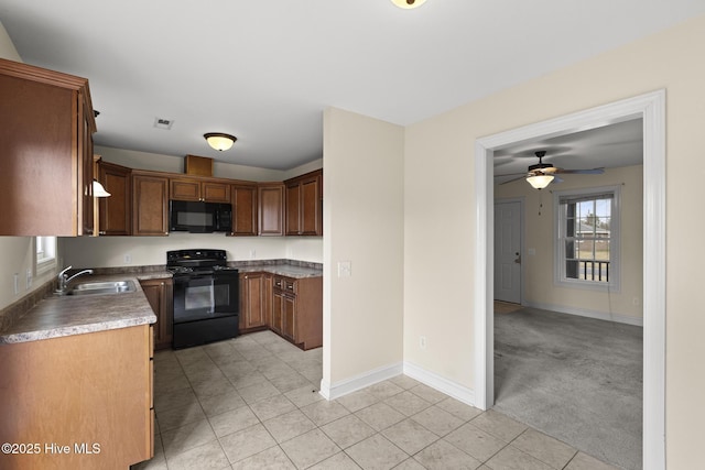 kitchen featuring light tile patterned floors, visible vents, a sink, black appliances, and light colored carpet