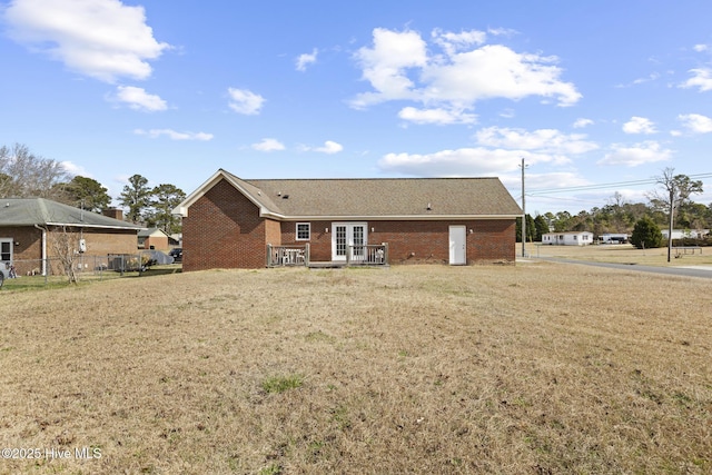 back of house with french doors, brick siding, and a lawn