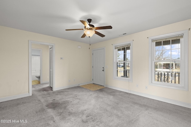 carpeted empty room with visible vents, baseboards, and a ceiling fan