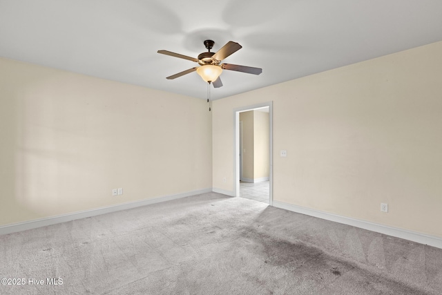 carpeted spare room featuring a ceiling fan and baseboards