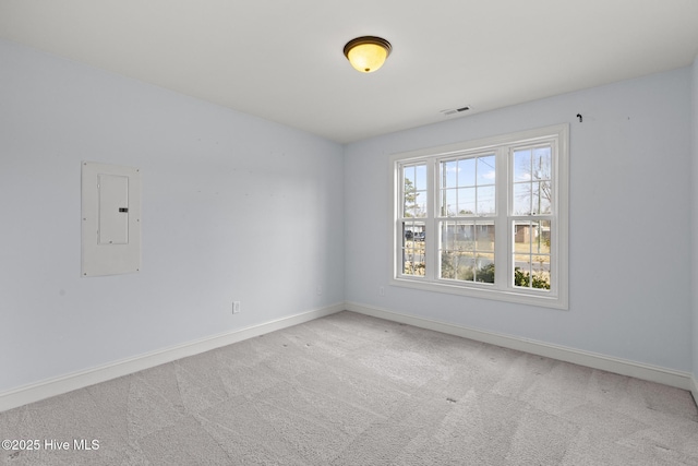 carpeted spare room featuring electric panel, visible vents, and baseboards