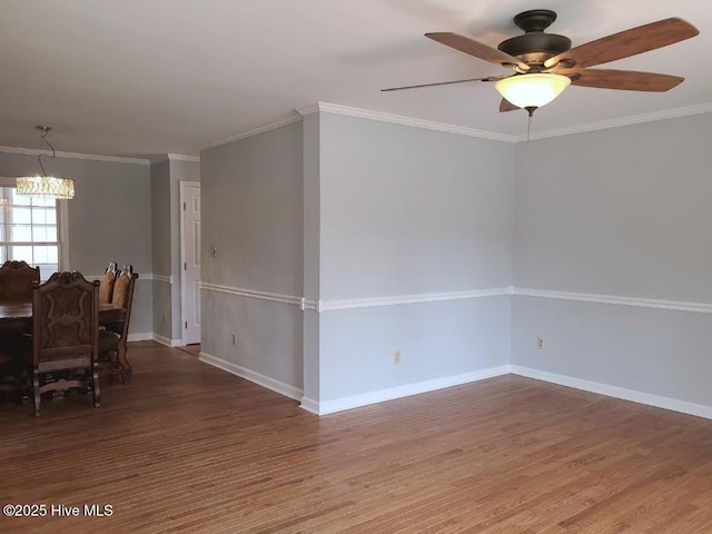 empty room with crown molding, baseboards, and wood finished floors