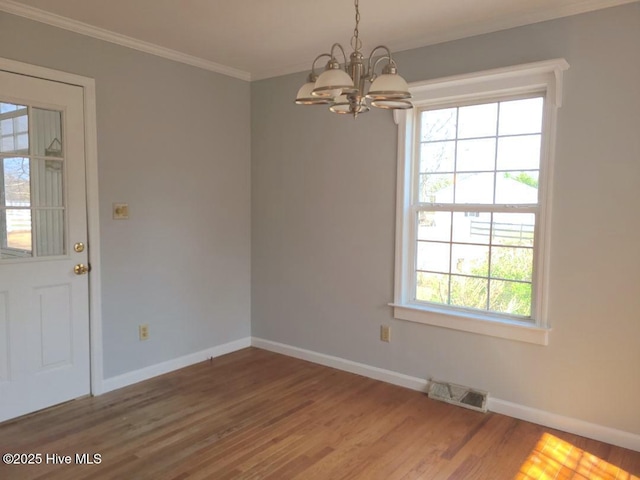 unfurnished room featuring visible vents, crown molding, baseboards, wood finished floors, and a notable chandelier