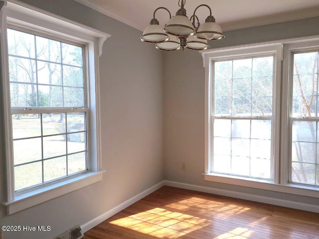 unfurnished dining area featuring crown molding, a notable chandelier, baseboards, and plenty of natural light