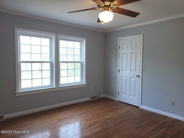 empty room featuring baseboards, wood finished floors, visible vents, and ornamental molding