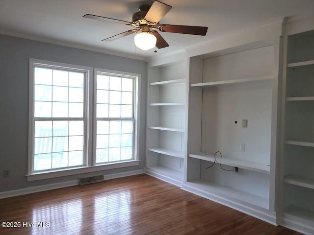 interior space featuring visible vents, built in shelves, a ceiling fan, wood finished floors, and crown molding