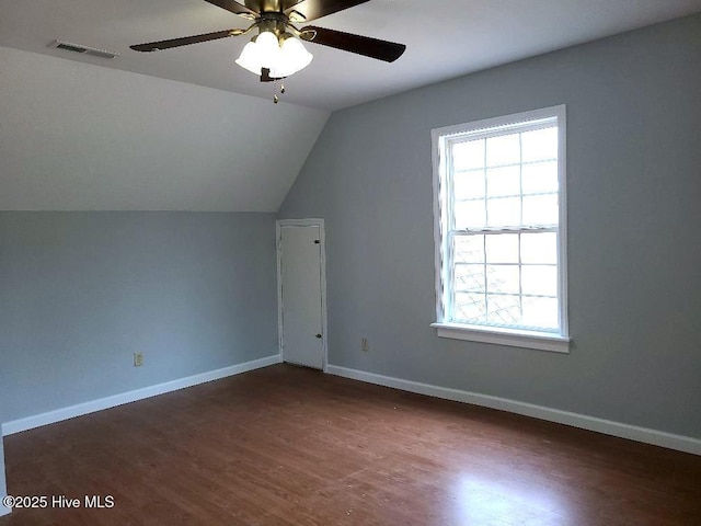 additional living space with visible vents, baseboards, vaulted ceiling, wood finished floors, and a ceiling fan