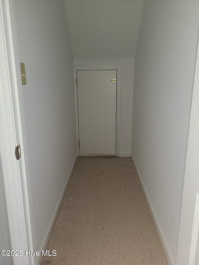 corridor featuring baseboards and vaulted ceiling