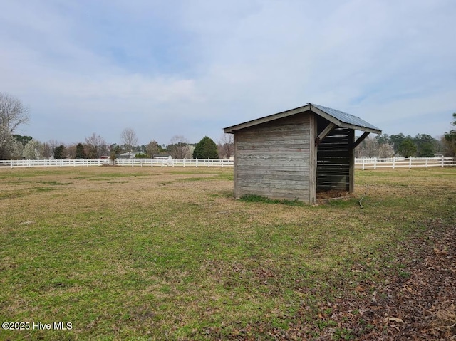 view of outbuilding featuring a rural view, an outdoor structure, and fence