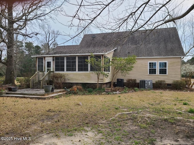 view of front facade with a front lawn, central AC, roof with shingles, a sunroom, and crawl space