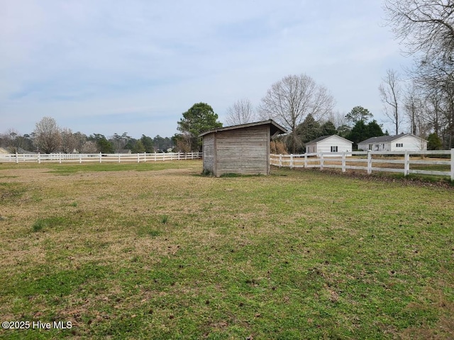 view of yard with a rural view, an outbuilding, and fence