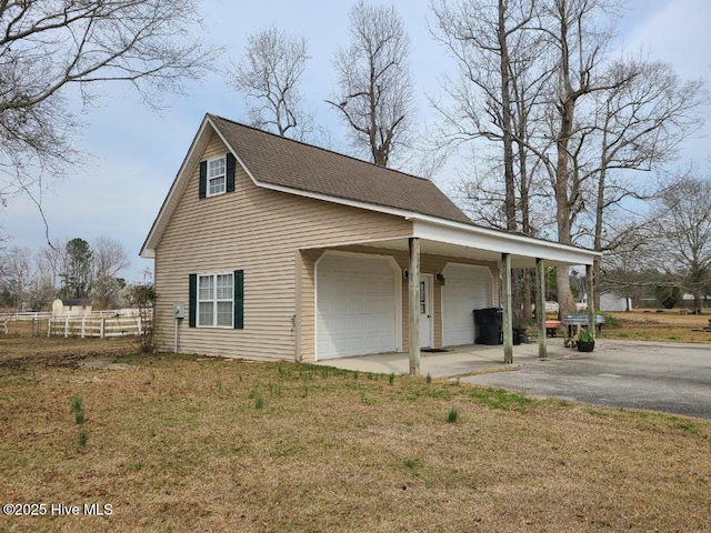 view of home's exterior featuring fence, a garage, driveway, and a lawn