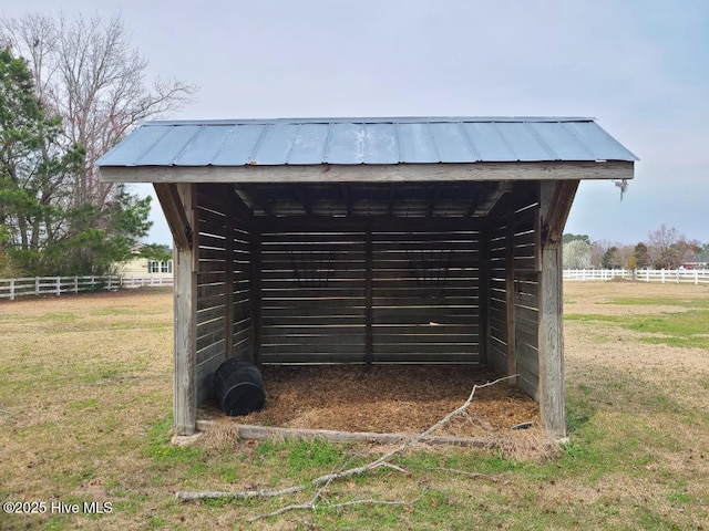 view of outbuilding with a rural view, an outdoor structure, and fence