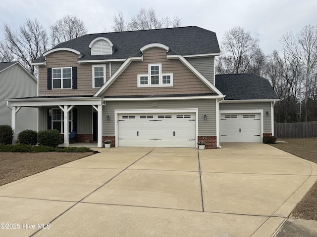 view of front of home featuring a shingled roof, fence, concrete driveway, covered porch, and an attached garage