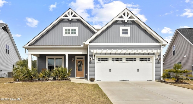 view of front facade featuring central AC unit, driveway, a porch, a garage, and board and batten siding