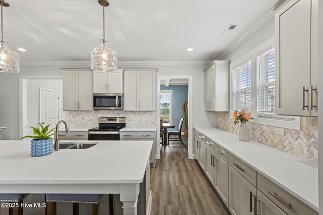 kitchen with a sink, light countertops, crown molding, and stainless steel appliances