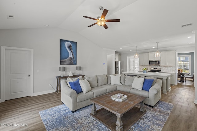 living room featuring lofted ceiling, light wood-style floors, and ornamental molding