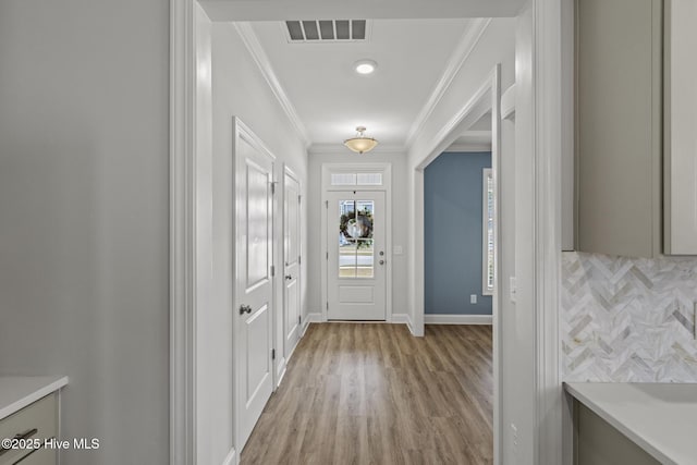 doorway to outside featuring visible vents, light wood-style flooring, baseboards, and ornamental molding