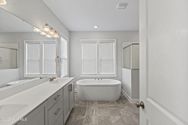 bathroom with visible vents, a shower stall, double vanity, a soaking tub, and a sink