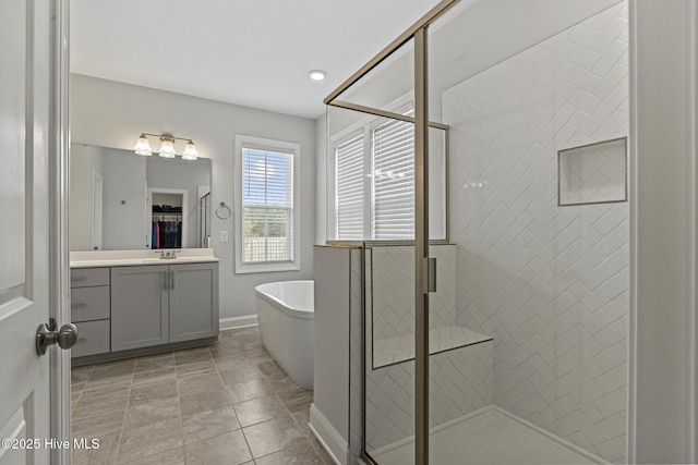 full bathroom with a walk in closet, a shower stall, baseboards, a soaking tub, and vanity