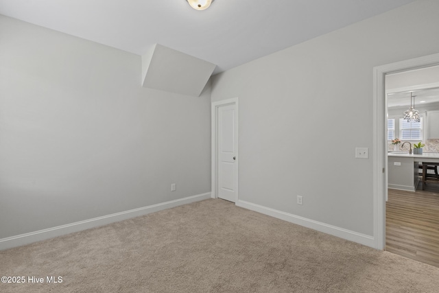 interior space featuring carpet flooring, baseboards, and a chandelier