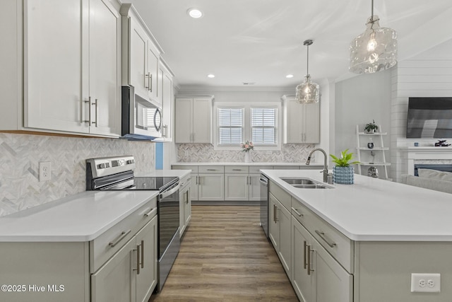 kitchen featuring a sink, open floor plan, stainless steel appliances, light countertops, and decorative backsplash