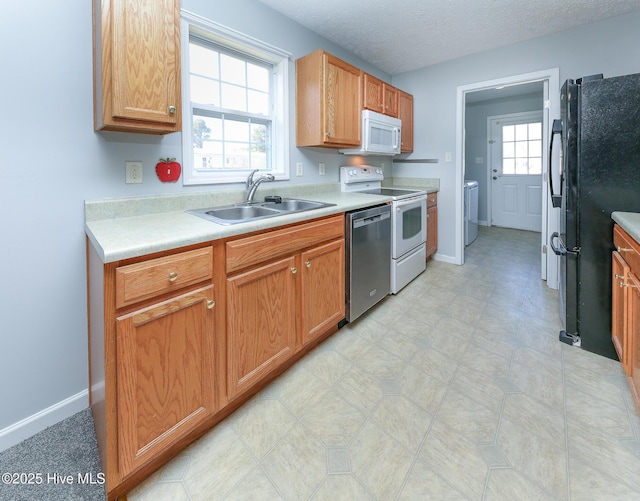 kitchen featuring white appliances, a textured ceiling, light countertops, and a sink