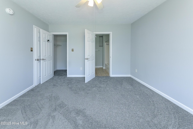 unfurnished bedroom with baseboards, carpet floors, a textured ceiling, and a spacious closet