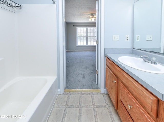 bathroom with vanity, a ceiling fan, a bathing tub, and a textured ceiling