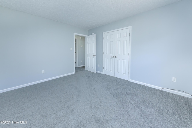 unfurnished bedroom featuring baseboards, a closet, a textured ceiling, and carpet