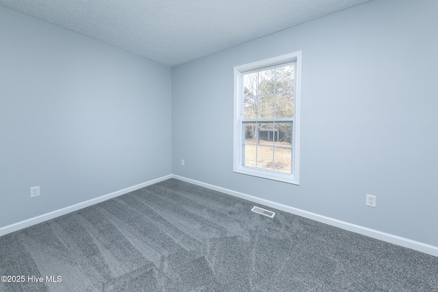 spare room with visible vents, dark carpet, a textured ceiling, and baseboards