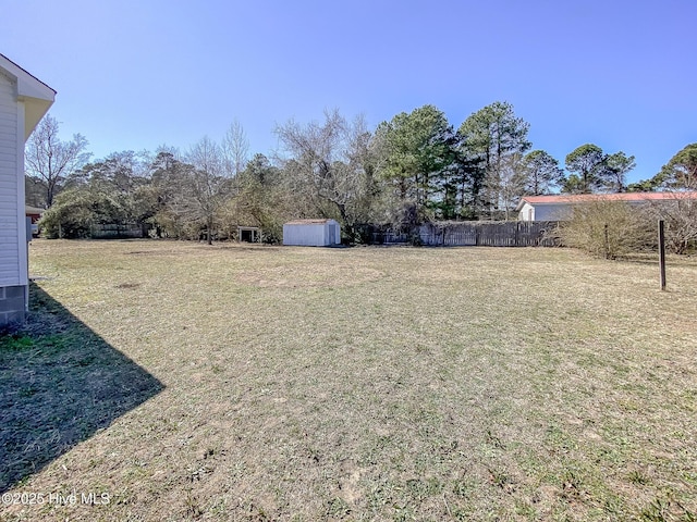 view of yard with an outbuilding, fence, and a shed