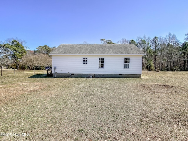 rear view of property with crawl space, a yard, and roof with shingles