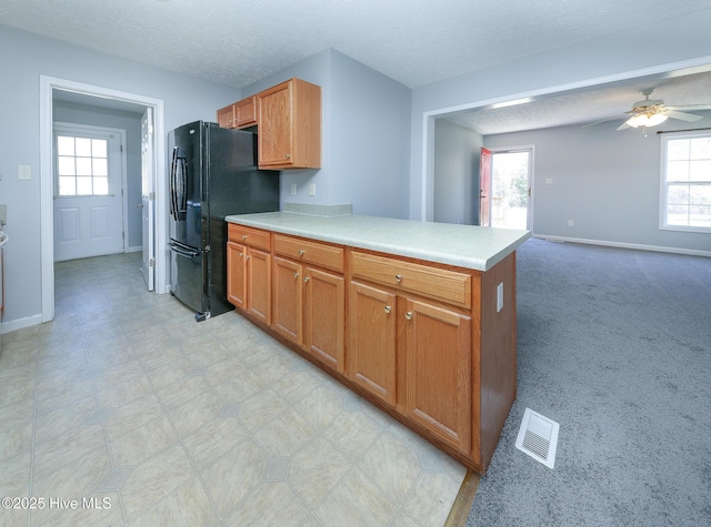 kitchen featuring visible vents, freestanding refrigerator, a peninsula, light countertops, and ceiling fan