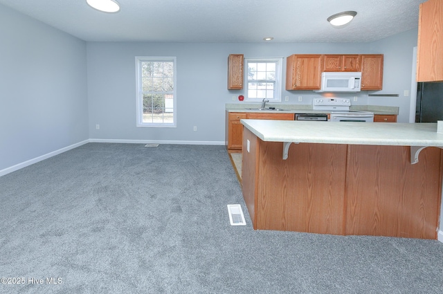 kitchen featuring white appliances, visible vents, a sink, light countertops, and a kitchen breakfast bar