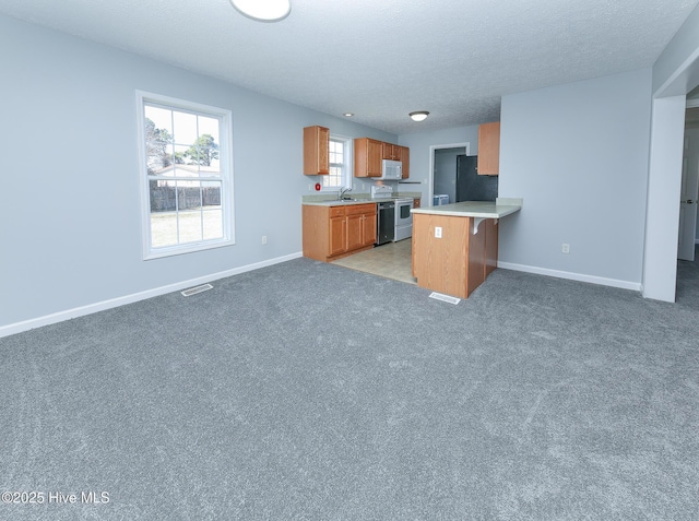 kitchen with open floor plan, white appliances, light countertops, and a peninsula